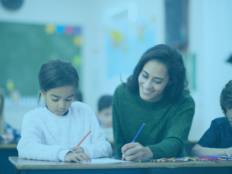 teacher helping student at desk