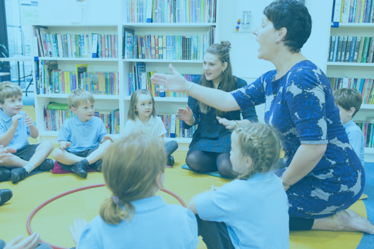 teacher making sign to students sitting in a circle