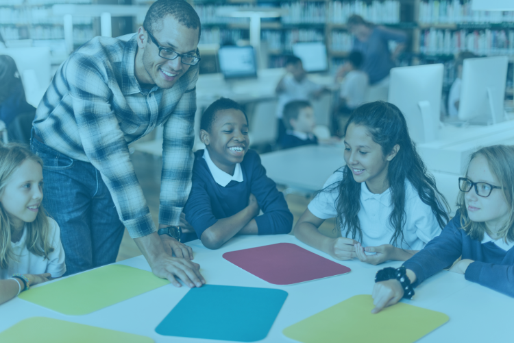 teacher talks to group of students at desk